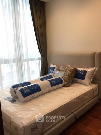 Cozy bedroom with plush bedding and large window for natural light.