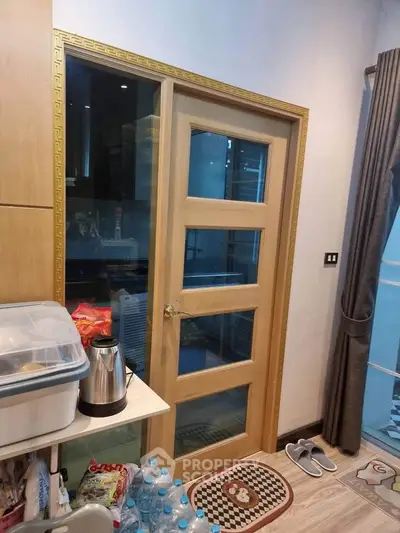 Modern kitchen with wooden door and glass panels, featuring sleek appliances and organized storage.