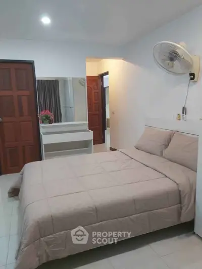 Cozy bedroom with neutral decor and wall-mounted fan, perfect for restful nights.