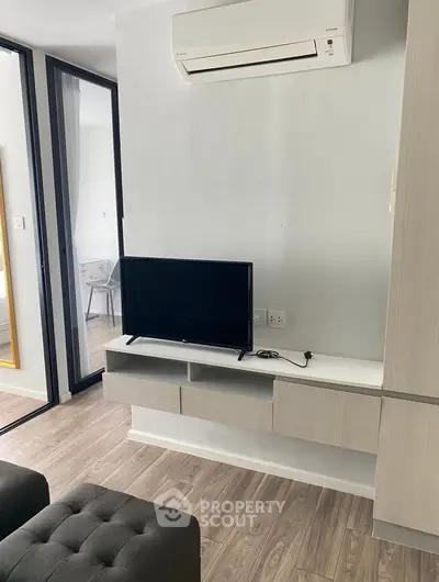 Modern living room with wall-mounted TV and air conditioning in a stylish apartment.