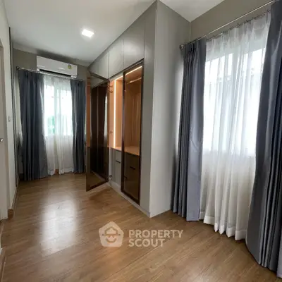 Spacious bedroom with elegant wooden flooring and ample natural light