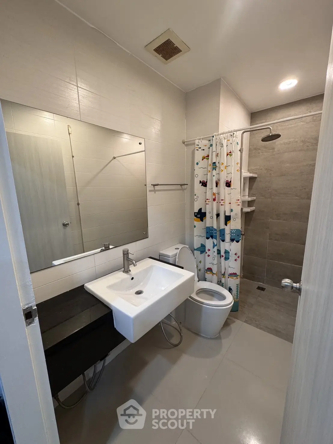 Modern bathroom with sleek fixtures and playful shower curtain in a contemporary apartment.