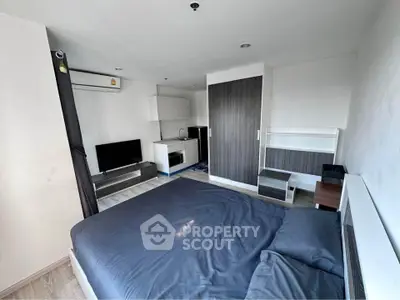 Modern studio apartment with sleek design, featuring a cozy bed, compact kitchen, and stylish living area.