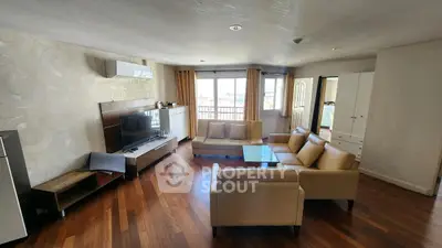 Spacious living room with modern furniture and wooden flooring, featuring a large window with a view.