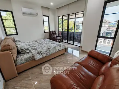 Spacious bedroom with large windows and balcony access, featuring modern furnishings and natural light.