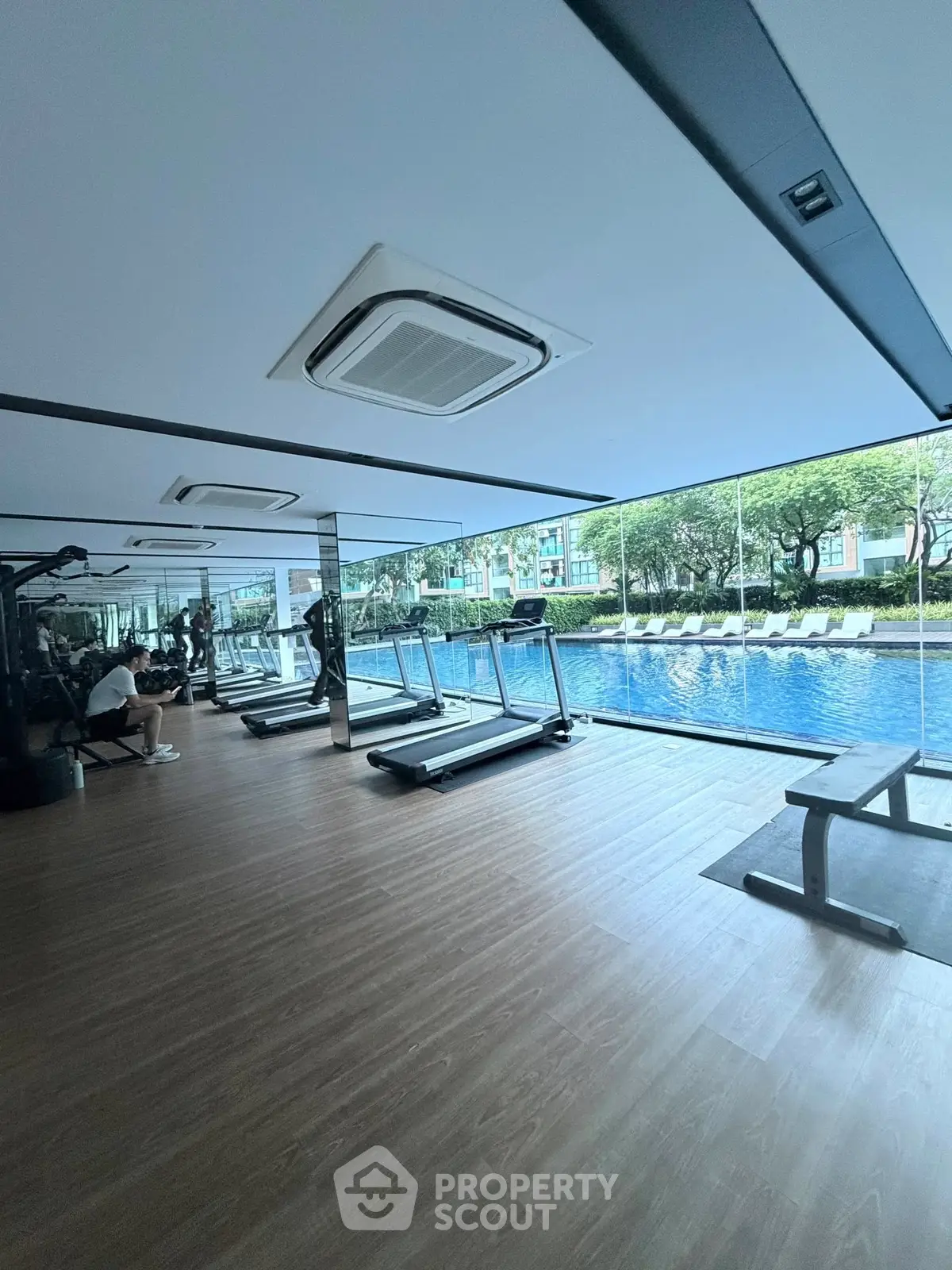 Modern gym with pool view and state-of-the-art equipment in luxury residential complex.
