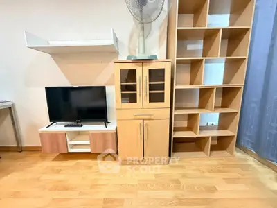 Modern living room with wooden flooring, TV stand, and spacious shelving unit.