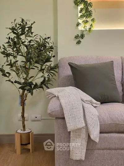 Cozy living room corner with plush sofa, decorative plant, and soft lighting.