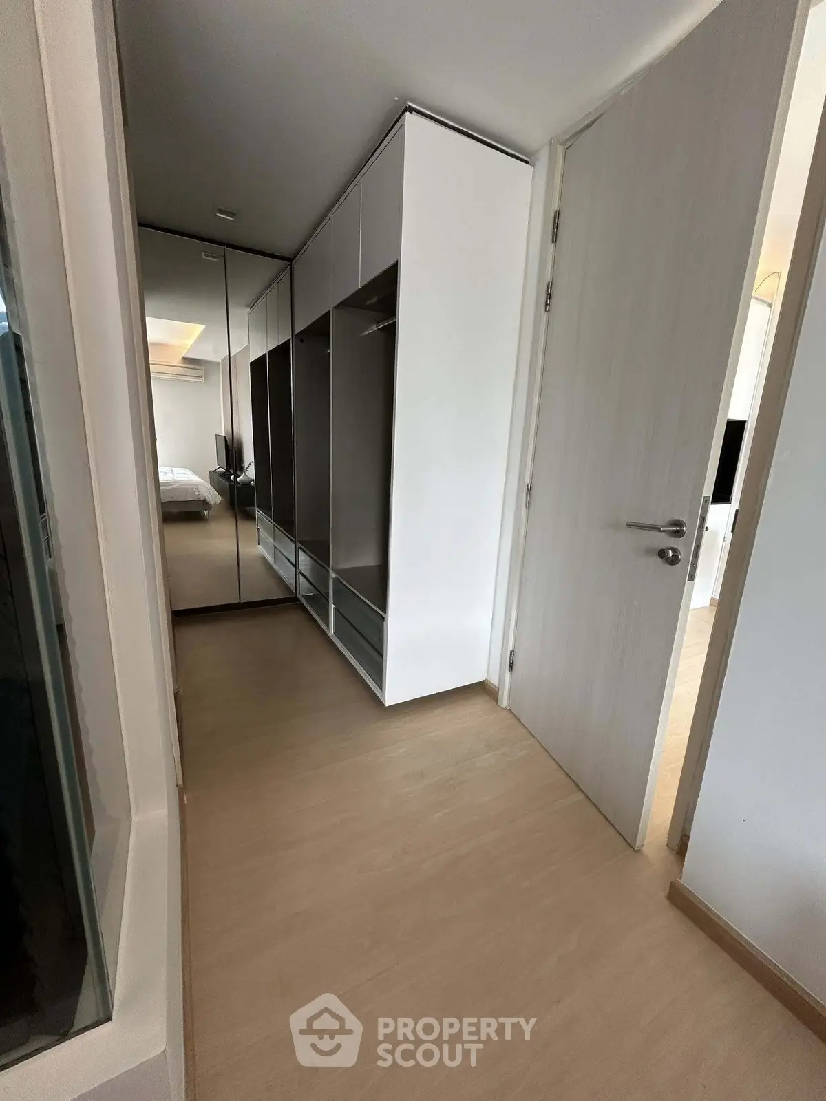 Modern bedroom with sleek wardrobe and wooden flooring, showcasing minimalist design and ample storage space.