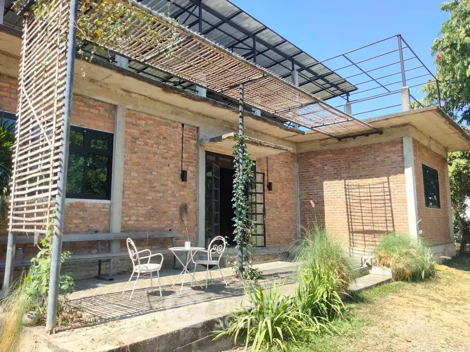 Charming brick exterior house with rustic patio and lush greenery