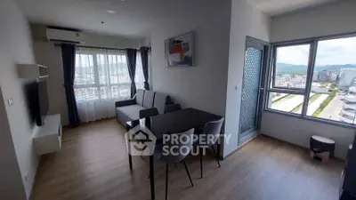 Modern living room with dining area and city view, featuring sleek furniture and large windows.