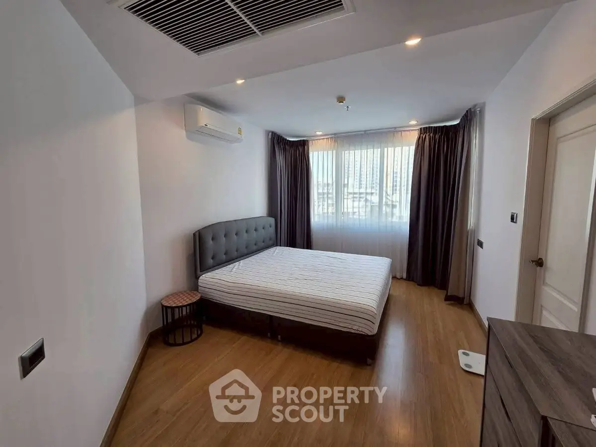 Modern bedroom with wooden flooring and natural light