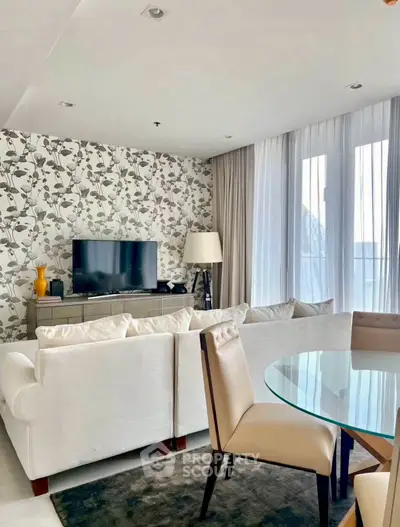 Stylish living room with modern decor, featuring a cozy sofa, flat-screen TV, and elegant dining area.