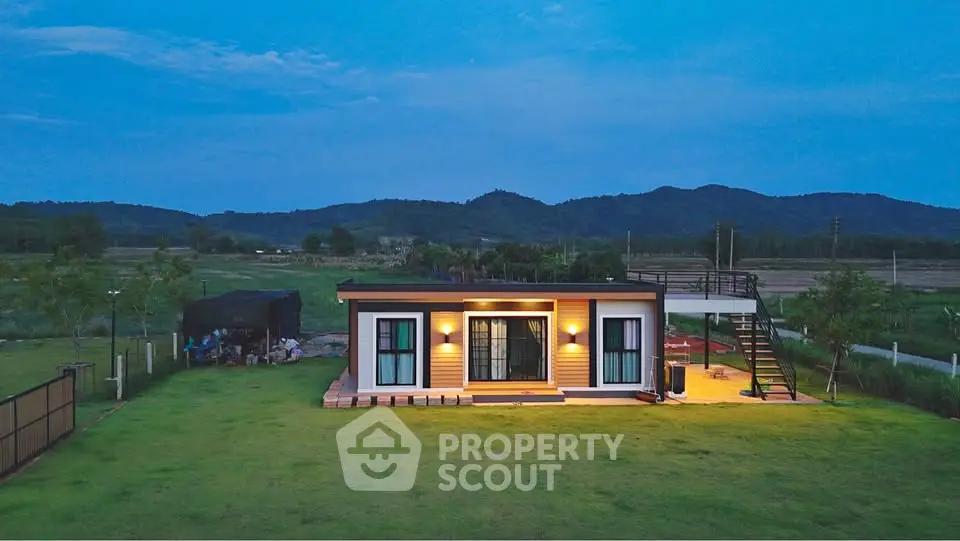 Charming modern tiny house with scenic mountain backdrop and spacious green lawn.