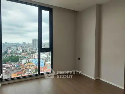 Spacious room with large window offering stunning city view in modern apartment.