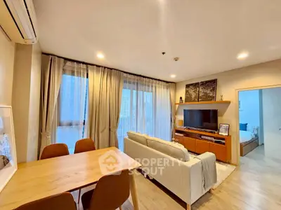 Modern living room with cozy seating and dining area, featuring large windows and stylish decor.