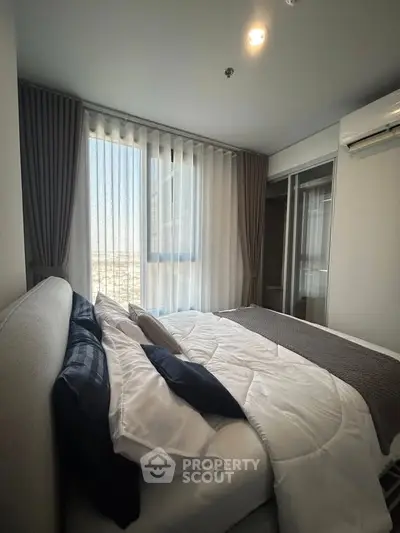 Modern bedroom with large window and stylish decor in high-rise apartment.
