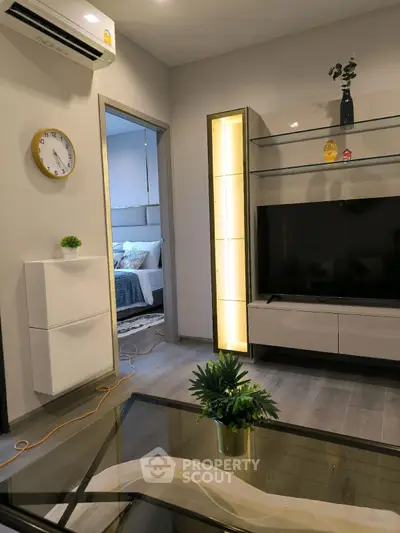 Modern living room with sleek TV unit and stylish decor, leading to a cozy bedroom.