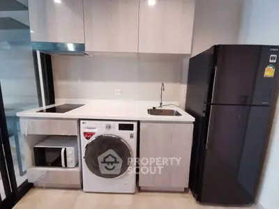 Modern kitchen with sleek appliances including washing machine and fridge in compact layout.