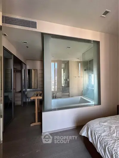 Luxurious bedroom with glass-walled bathroom featuring a modern bathtub and sleek design.