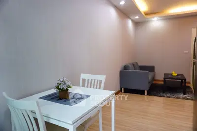 Modern living room with cozy seating and dining area, featuring elegant lighting and wooden flooring.