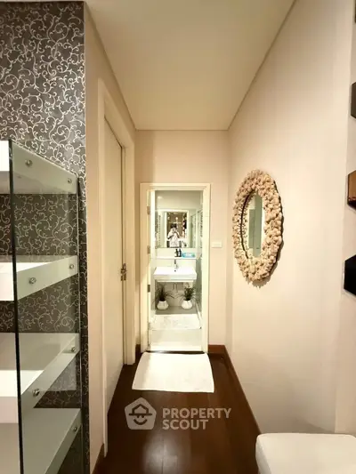 Elegant bathroom with stylish decor and modern fixtures, featuring a unique wall mirror and sleek shelving.