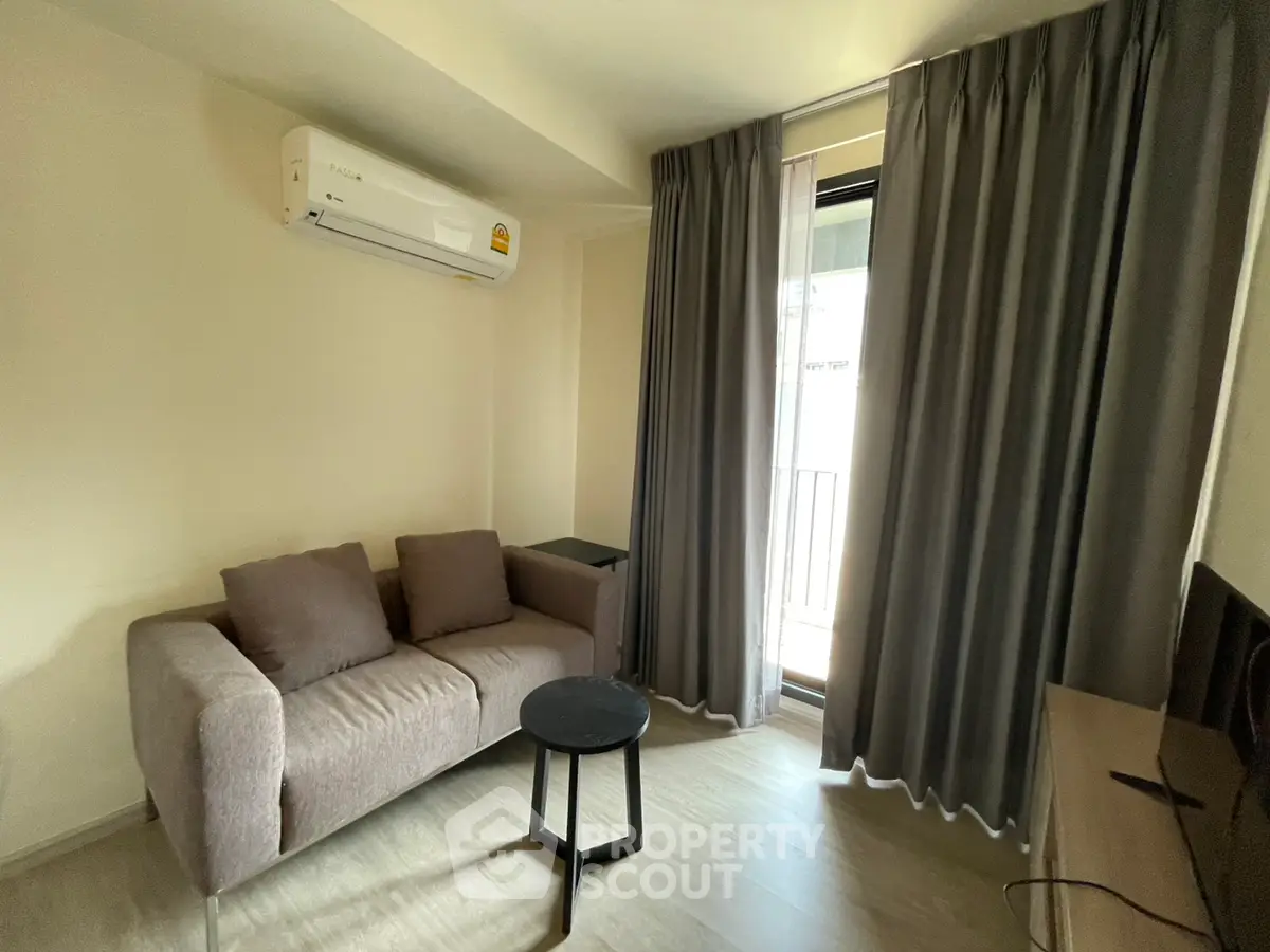 Cozy living room with modern sofa, air conditioning, and balcony access in a stylish apartment.