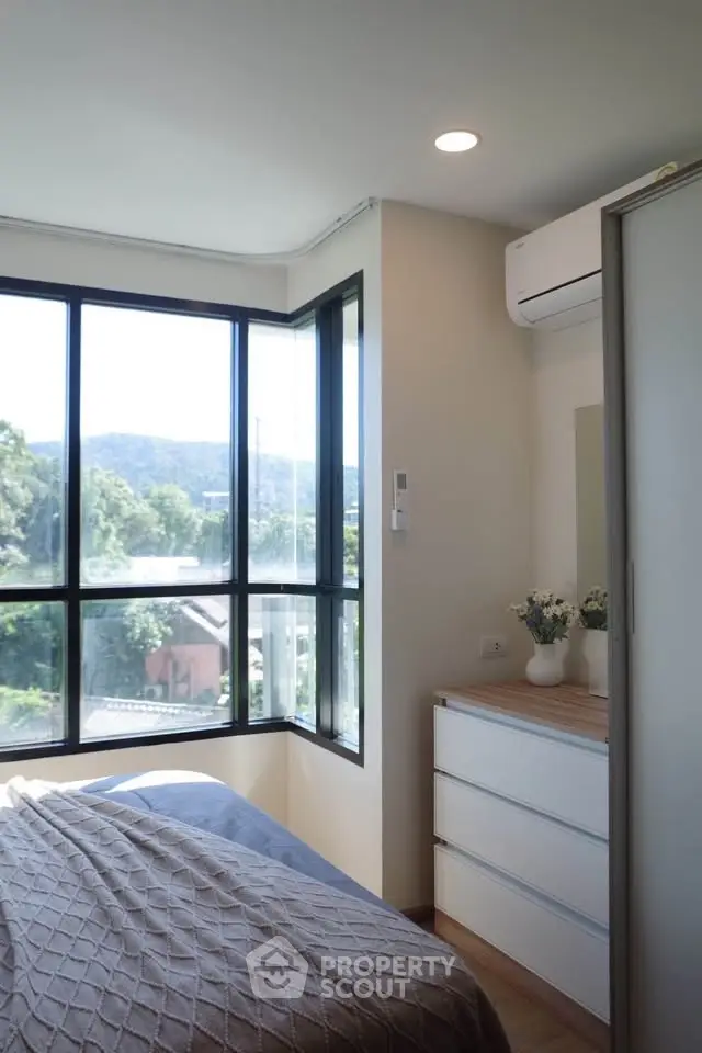 Bright bedroom with large windows offering scenic views and modern decor.