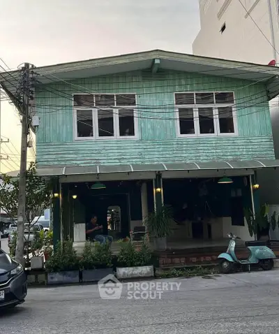 Charming vintage two-story wooden house with rustic facade and cozy porch, perfect for urban living.