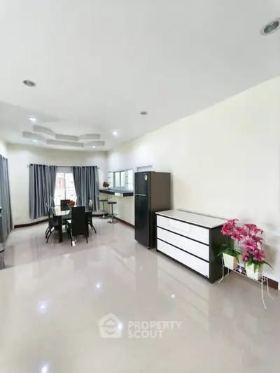 Spacious open-plan living area with modern dining set and sleek appliances