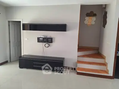 Modern living room with sleek black furniture and wooden staircase