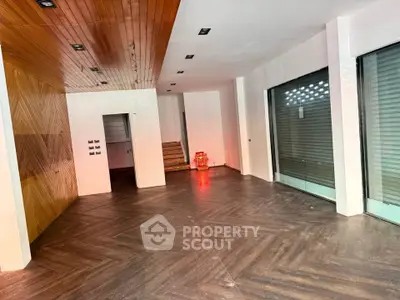 Spacious modern interior with wooden flooring and large windows, ideal for retail or office space.