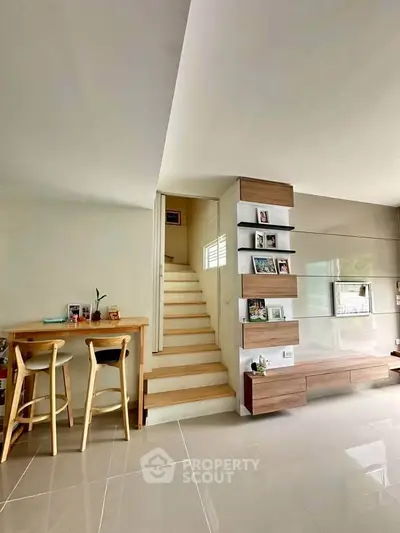 Modern living room with stylish staircase and cozy dining area, perfect for contemporary living.