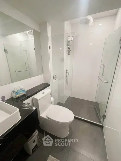 Modern bathroom with glass shower and sleek fixtures in contemporary apartment.