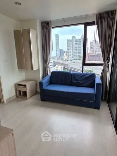 Modern living room with blue sofa and city view from large windows.