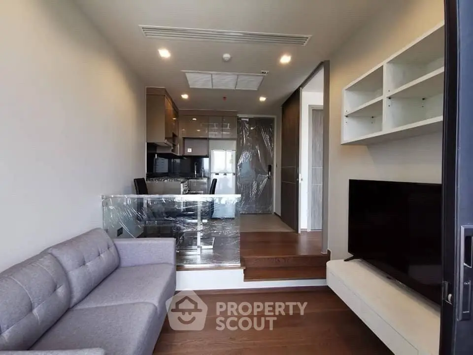 Modern living room with open kitchen, sleek furniture, and stylish lighting in a contemporary apartment.