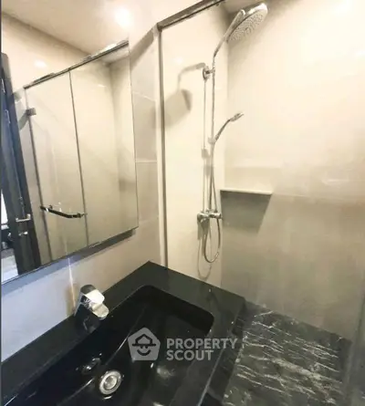 Modern bathroom with sleek black sink and glass shower enclosure.