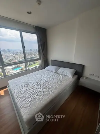 Modern bedroom with stunning city view and large windows in high-rise apartment.