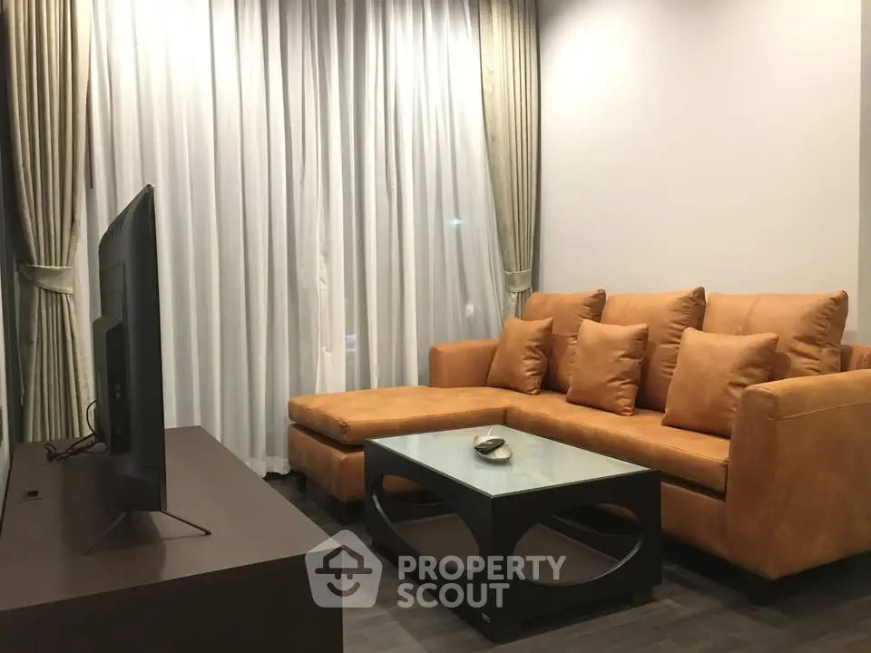 Modern living room with stylish brown leather sofa and sleek TV setup.