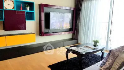 Modern living room with stylish TV unit and natural light from balcony.
