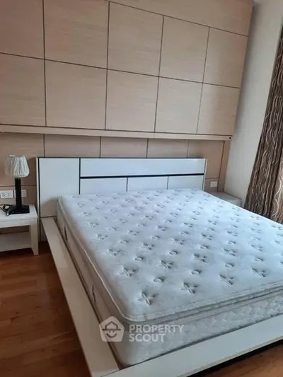 Spacious bedroom with modern design and large bed, featuring elegant wooden paneling and natural light.