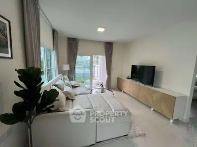 Spacious modern living room with large sofa and TV, featuring natural light and elegant decor.