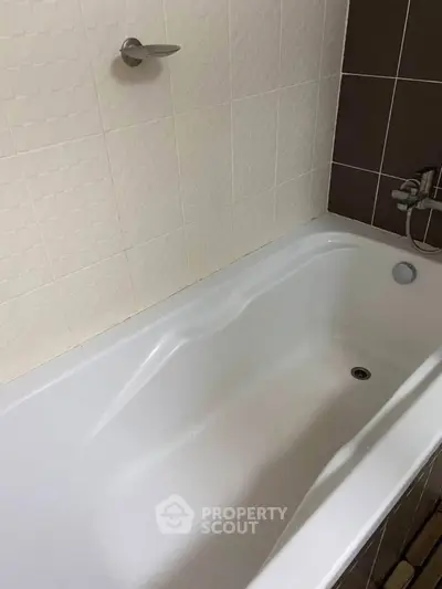 Modern bathroom with sleek white bathtub and stylish tile design.