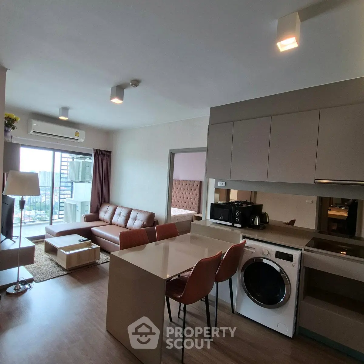 Modern open-plan living room with kitchen and laundry area, featuring stylish furniture and natural light.