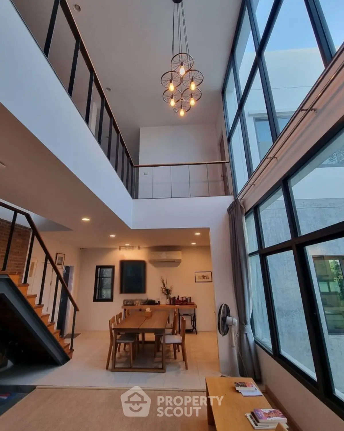 Stunning modern duplex with high ceilings and elegant dining area, featuring large windows and stylish lighting.