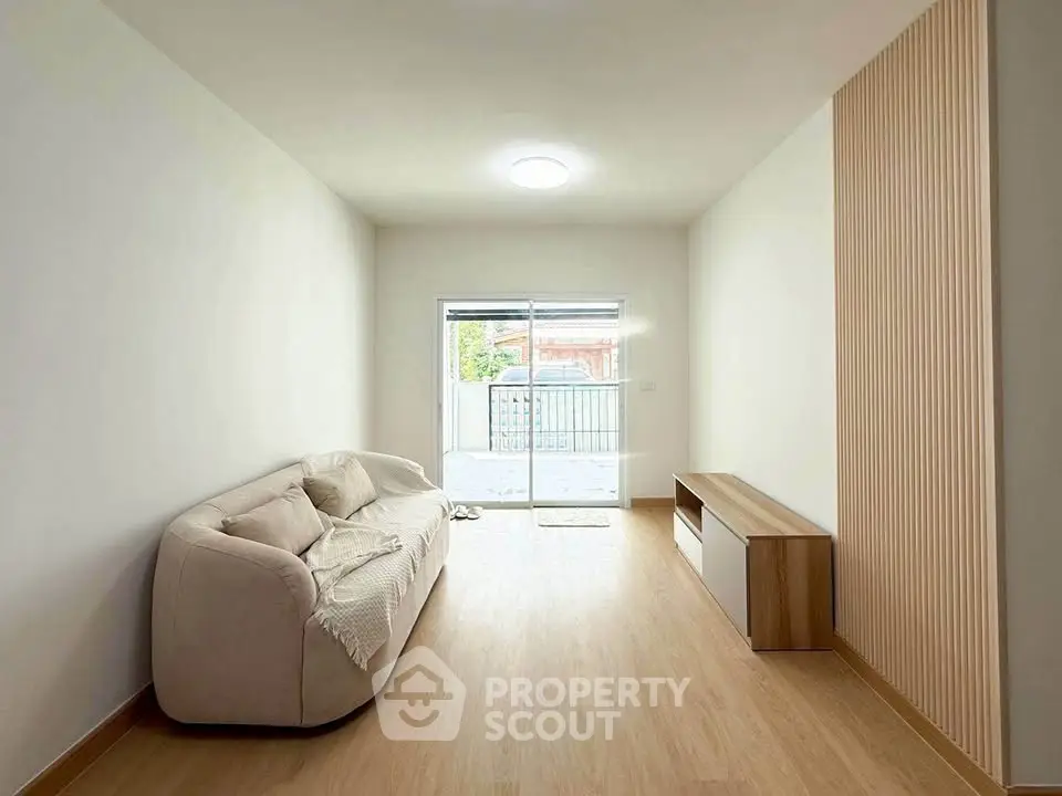 Spacious minimalist living room with cozy sofa and natural light from balcony.