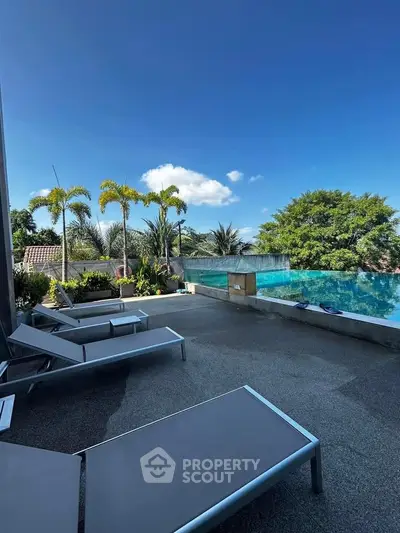 Luxurious outdoor pool area with sun loungers and tropical landscaping, perfect for relaxation and leisure.