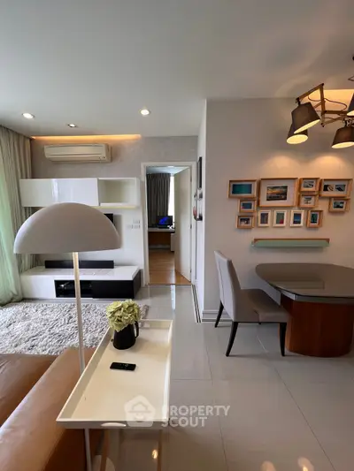 Modern living room with stylish decor and cozy dining area, featuring elegant lighting and wall art.