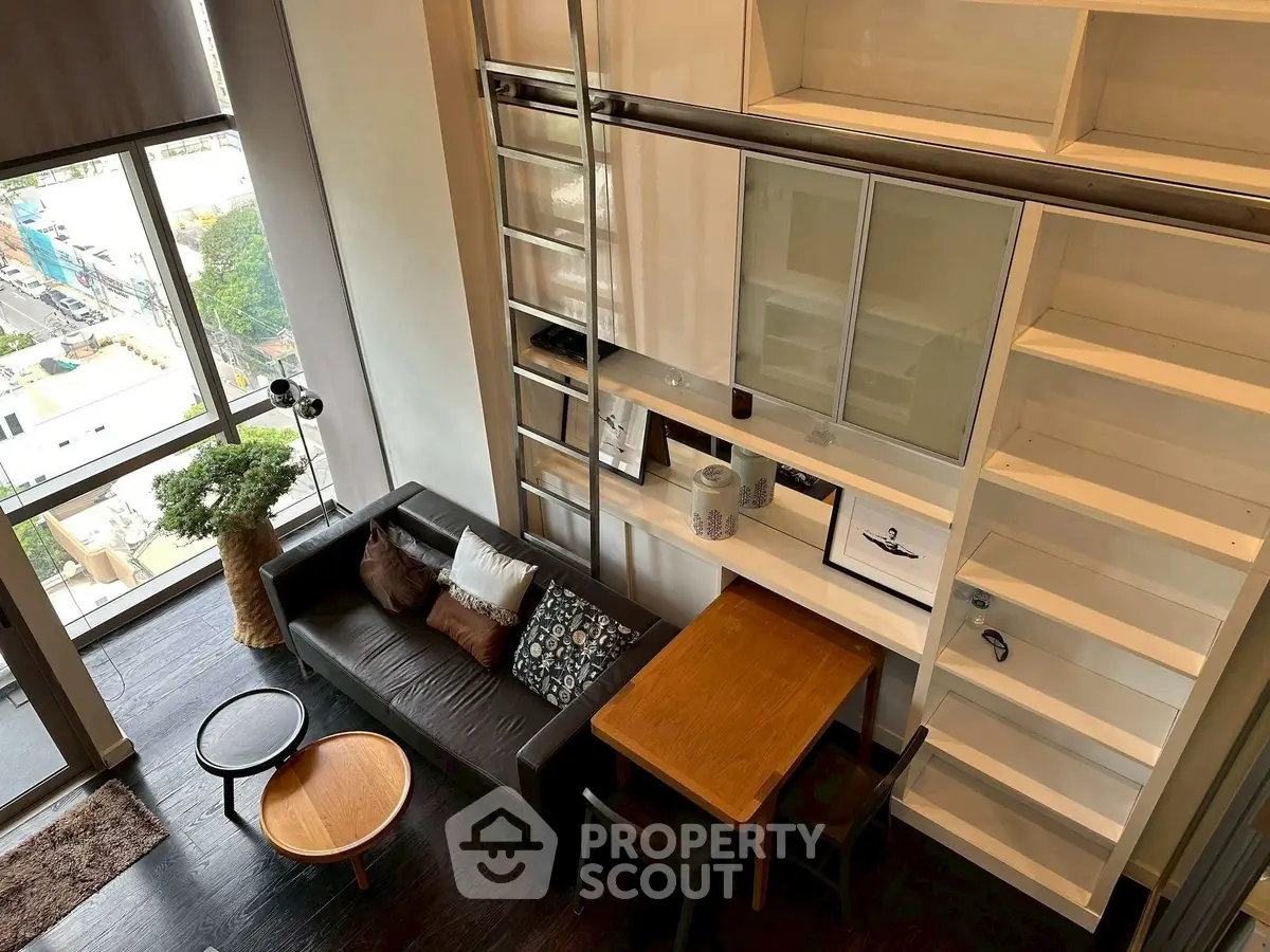 Modern loft apartment with high ceilings, large windows, and stylish furniture in a cozy living area.