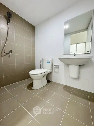 Modern bathroom with sleek fixtures and neutral tiles, featuring a shower and large mirror.